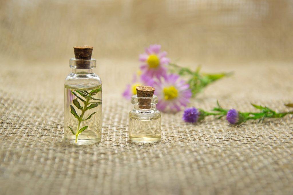 Two Essential Oil Bottles With Flowers in Background